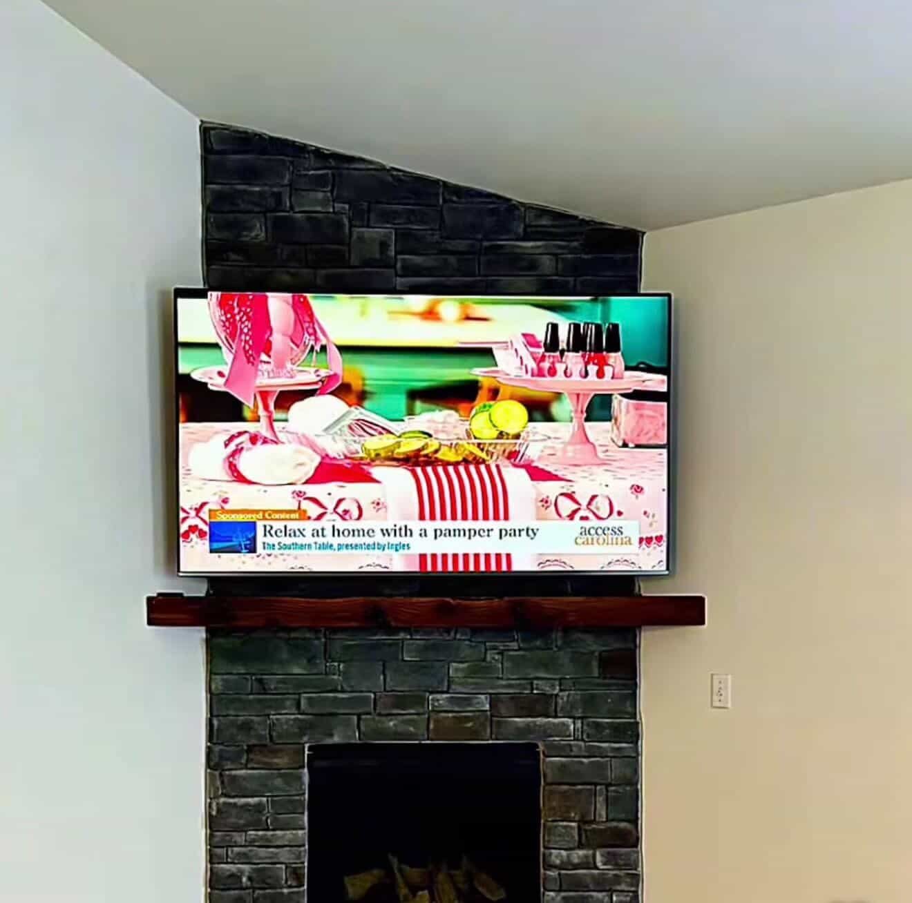 TV mounted above a stone fireplace by Elevated Entertainment